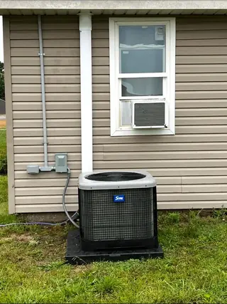 Outdoor residential HVAC condenser installed below a window